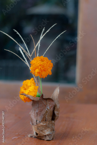 Artistic Marigold Flower Arrangement in Natural Dried Leaf Vase on Wooden Surface