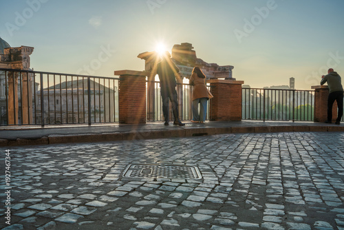 Tourist couple visit Temple of Saturn at Roman forum ruins onsunrise in Rome. Italy