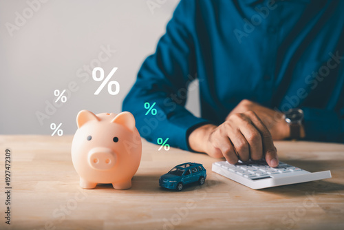 Bild auf Leinwand Man calculates car loan with piggy bank, saving money for auto insurance payment