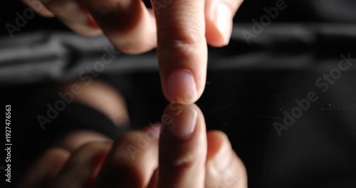 Closeup of fingers touching surface.