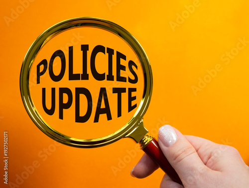 Policies Update symbol. Magnifying Glass with words Policies Update. Businessman hand. Beautiful orange background. Business and Policies Update concept. Copy space.