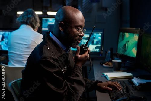 Canvas-taulu Blackman wearing security uniform monitoring surveillance footage and speaking i