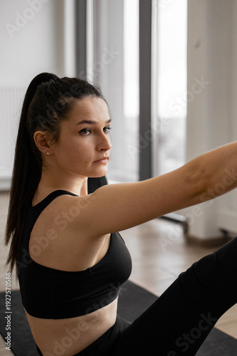 A focused woman in athletic wear performs a core strengthening exercise on a yoga mat in a bright, modern studio Free Download A focused woman in athletic wear performs a core strengthening exercise on a yoga mat in a bright, modern studio - GFXLoad