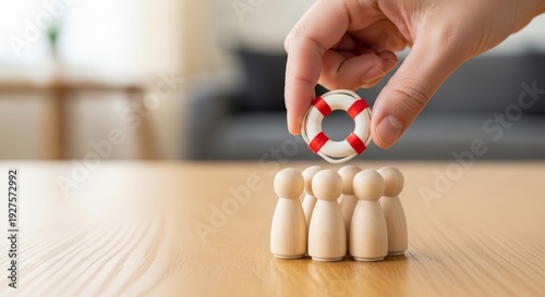 Hand offering a miniature life preserver to wooden figures