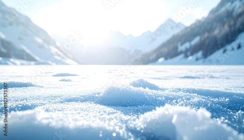 Snow-covered landscape with mountains under a bright sun. A frozen lake glistens in the distance