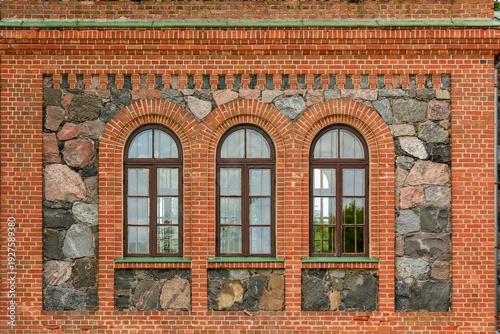 Historic facade features a combination of brick and stone with three arched windows.