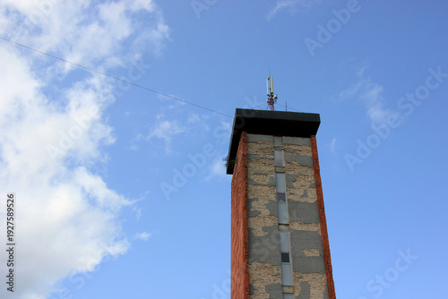 Weathered Communication Tower Against a Blue Sky with Clouds