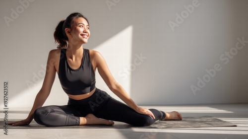 Beautiful asian woman smiles while stretching during her morning yoga routine.