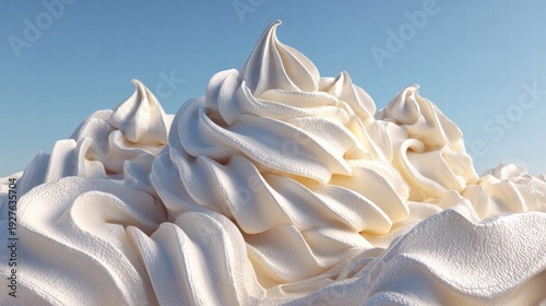 Close-up view of fluffy, white whipped cream swirls with a bright blue sky background.