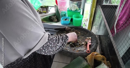 Woman preparing traditional clay or mud mixture in a large bowl.