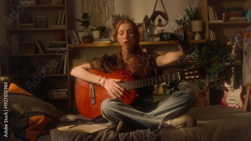 Wallpaper Mural Full length shot of red haired young woman playing acoustic guitar while sitting on bed at home and recording herself with retro video camera in cozy interior, copy space Torontodigital.ca