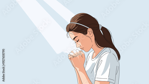 Young woman with her eyes closed and hands clasped in prayer stands peacefully under a bright ray of celestial light.