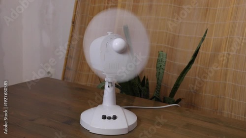 Desk fan operating with oscillating movement in three different positions demonstrating airflow for cooling and air circulation