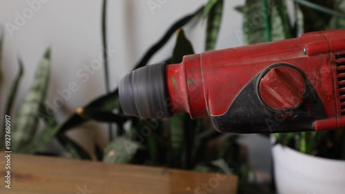 Red rotary hammer drill with spinning chuck for construction. Power tool renovation and DIY project concept.