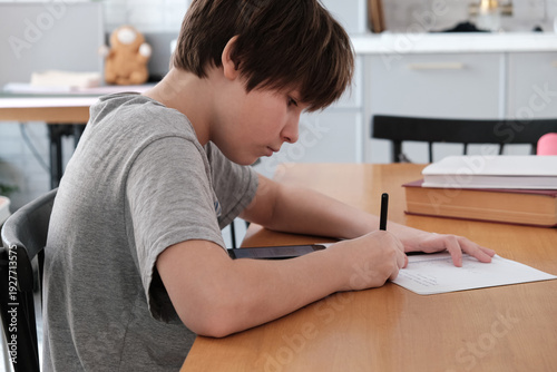 A teenager does his math homework, writes down examples in a notebook, and uses his smartphone for educational purposes. copying ready-made homework solutions. traditional and digital learning.