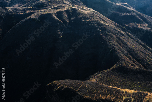 Mountain valley landscape with autumn forest and dramatic hills under blue sky