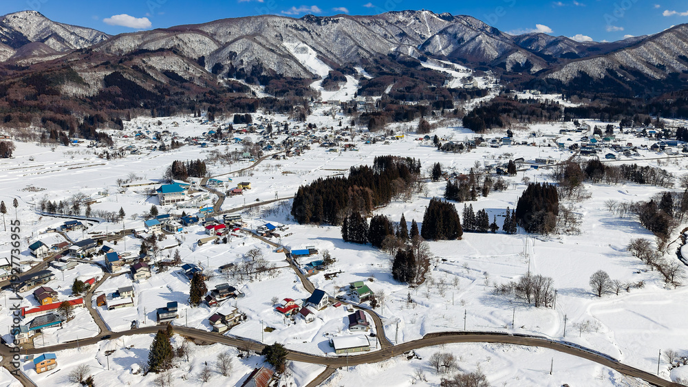 Naklejka premium Sunny winter day overlooking a snowy rural valley and mountains with blue sky