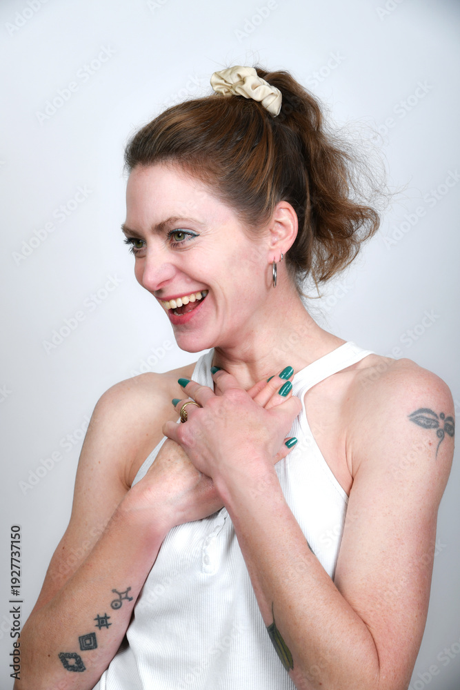 Obraz premium Natürliches Frauenportrait mit sanftem Lächeln und grün lackierten Nägeln. Warmes Licht, Tattoo-Detail und zarte Pose – modernes Beauty- und Lifestyle-Foto mit authentischer Ausstrahlung.