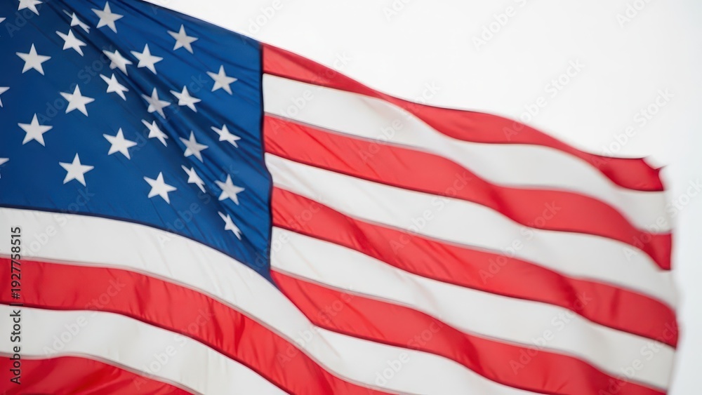 Fototapeta premium American flags waving in the wind against a blue sky with sunlight shining through, symbolizing patriotism and freedom from a low angle viewpoint on a sunny day outside.