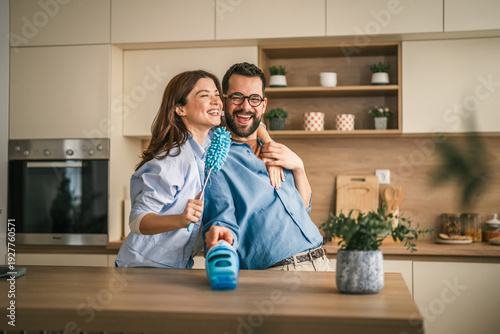 Photos Happy couple cleaning kitchen having fun together