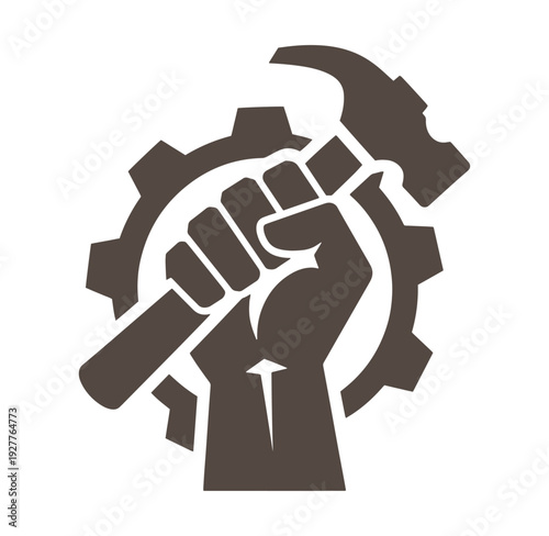 Brown fist holding hammer with gear in background symbolizing labor and industry