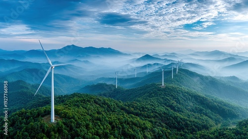 Wind turbines stand tall on misty green mountain ridges under a vast blue sky