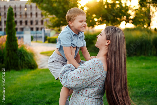 mom and child playing on a green lawn in the park in the summer, having fun together, mother and small child walking in the summer, playing on the grass