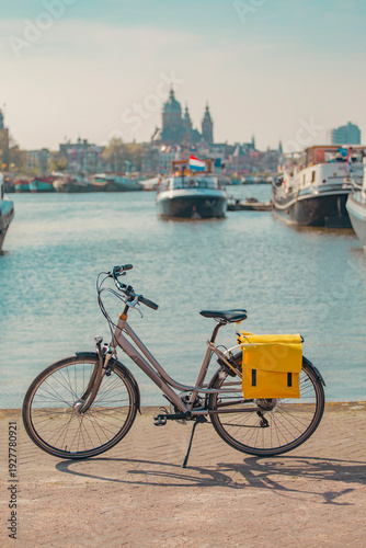 City bicycle with yellow pannier bag on Amsterdam canal quay with copy space in sky