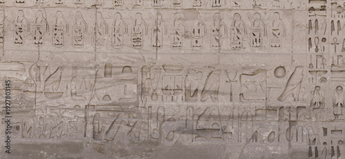 Ancient carved hieroglyphs depicting symbols on stone wall
