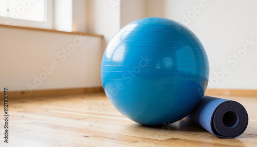 Blue exercise ball and yoga mat on a warm wooden floor in a bright, minimalist room for a fitness and wellness concept