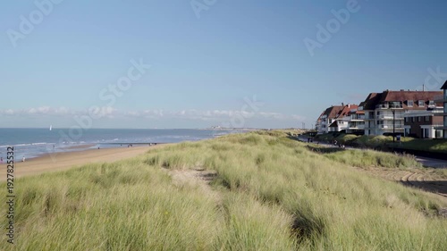 Pan from beach front houses over grass dune to knokke beach belgium