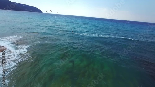 High-speed FPV drone chase following a kitesurfer riding across choppy water under dramatic storm clouds in Lefkada, Greece. Extreme water sport action powered by strong wind and rough sea conditions