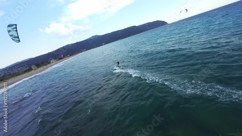 High-speed FPV drone chase following a kitesurfer riding across choppy water under dramatic storm clouds in Lefkada, Greece. Extreme water sport action powered by strong wind and rough sea conditions