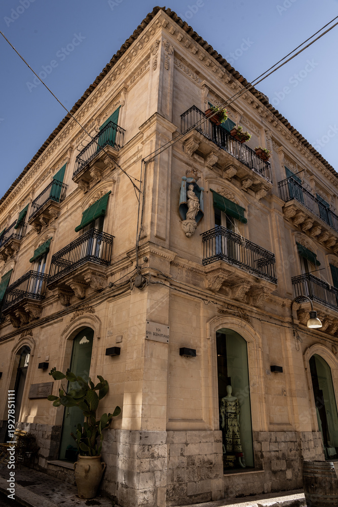 Fototapeta premium Sicilian baroque corner building with balconies and green shutters