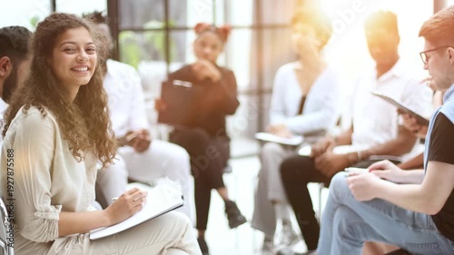 businesswoman with paper folder sitting near multiethnic colleagues during seminar