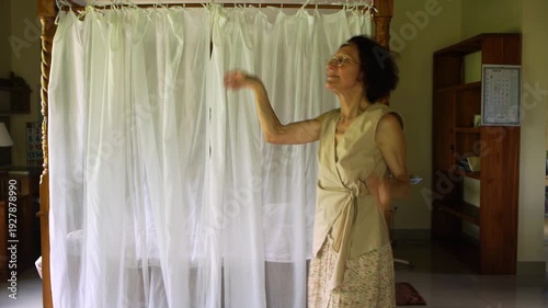 An elderly caucasian happy woman is dancing in her room, have fun, moves and feels overjoyed, celebrate good news.
