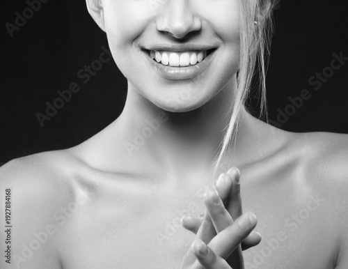 Close up lips and hands of beautiful young woman isolated on black background. Smile and happy