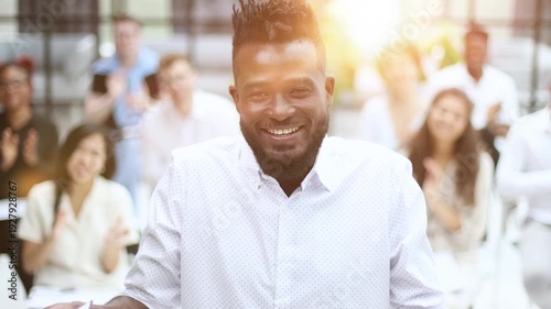 Team of happy male and female company workers applauding colleague in corporate meeting