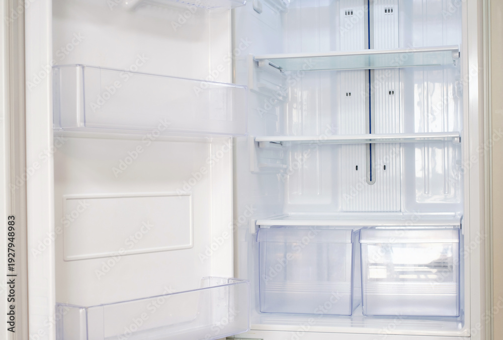 Fototapeta premium Modern open refrigerator close-up with empty shelves, front view.