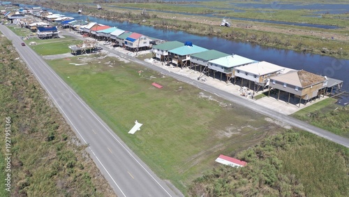 Aerial view of colorful stilt houses lining the waterway, beside the asphalt road, Delacroix, Louisiana, United States.