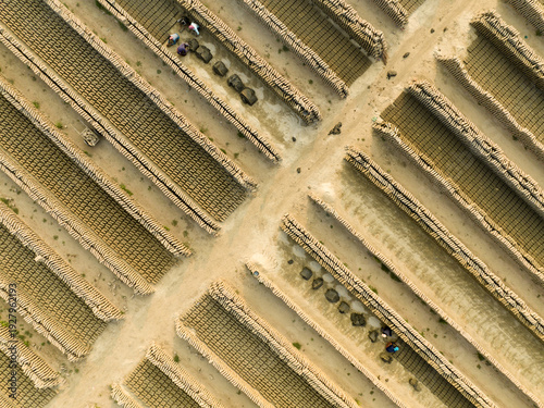 Aerial view of the rows of brick formations, with workers dispersed among them, create a textured geometric pattern, Aminbazar, Dhaka Division, Bangladesh.