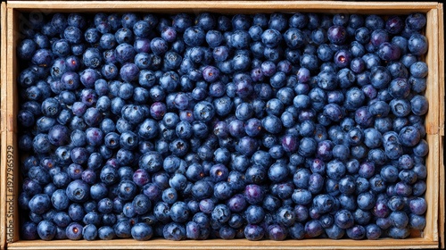 Fresh ripe blueberries filling wooden crate in top view