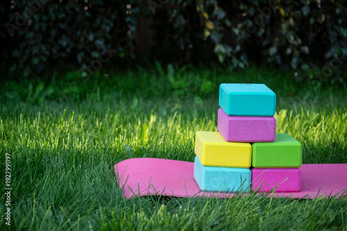 pink mat and colorful yoga blocks on green grass