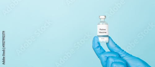 Obraz na płótnie Doctor hand holding Rabies vaccine bottle on blue background