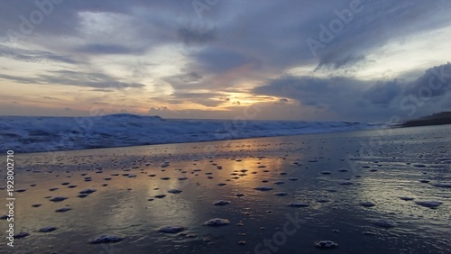Golden twilight sky over crashing sea waves and reflective shoreline, ideal for relaxation, inspiration, coastal tourism, and background design.