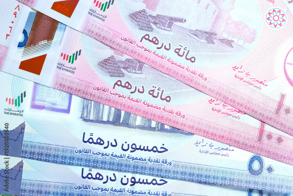 Fototapeta premium Close-up of United Arab Emirates Currency: AED Banknotes and Dirham Coins Scattered on Surface