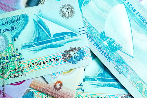 Close-up of United Arab Emirates Currency: AED Banknotes and Dirham Coins Scattered on Surface