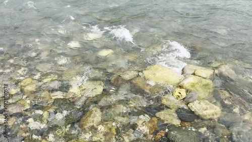 Crystal clear mountain water flows over smooth, sun-drenched stones, evoking tranquility and the raw beauty of nature, perfect for themes of serenity, exploration, or environmental awareness.
