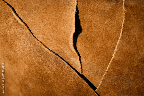 Closeup showing textured brown leather pieces overlapping in workshop setting, highlighting natural grain and raw edges, suitable for illustrating leathercraft or material quality
