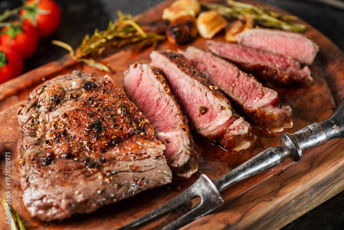 Fotografie Medium rare Ribeye steak with herbs a on the wooden tray.